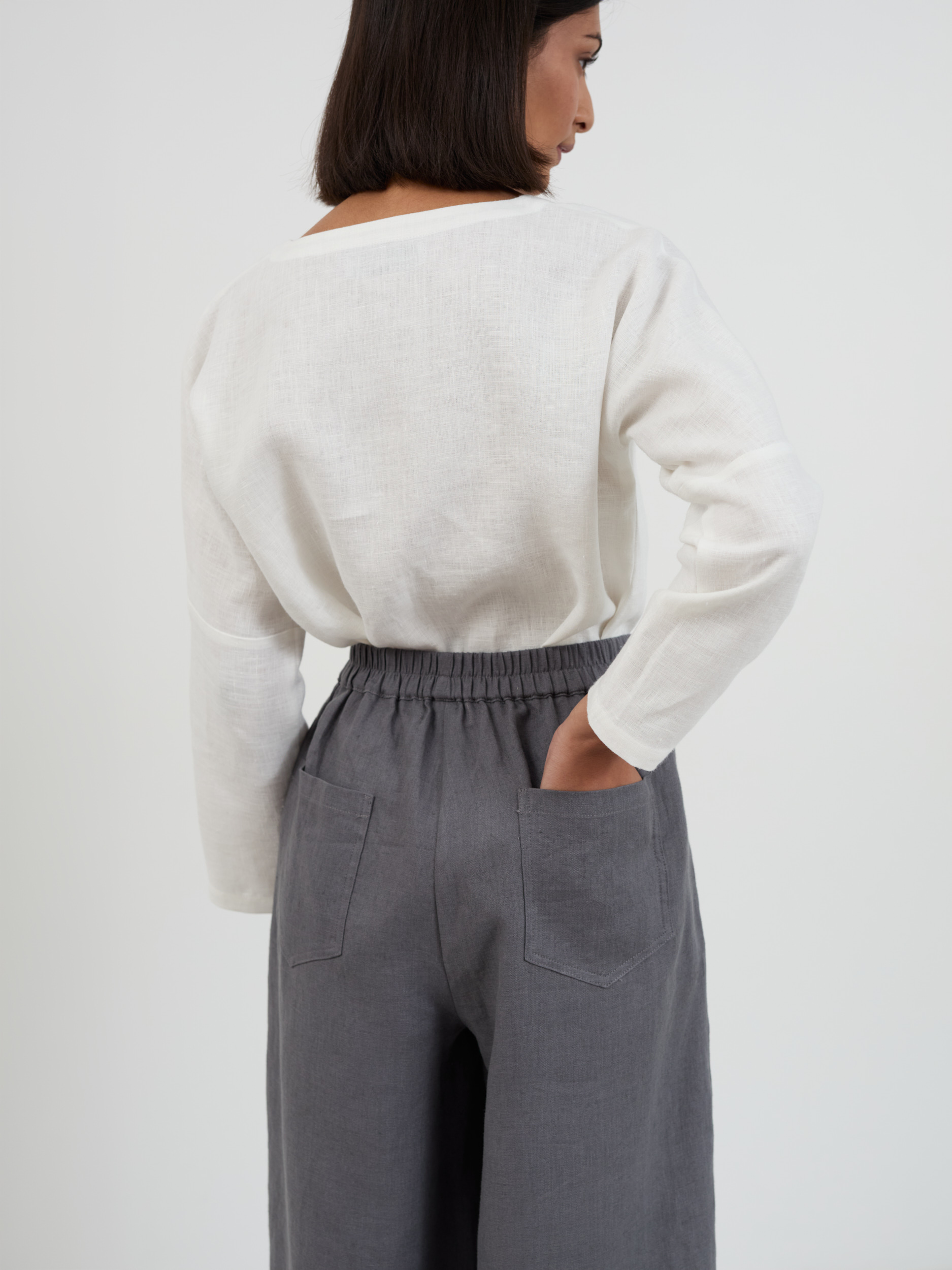 Back view of Haven charcoal linen pants showing two square back patch pockets, elasticated waistband, and relaxed fit through the seat