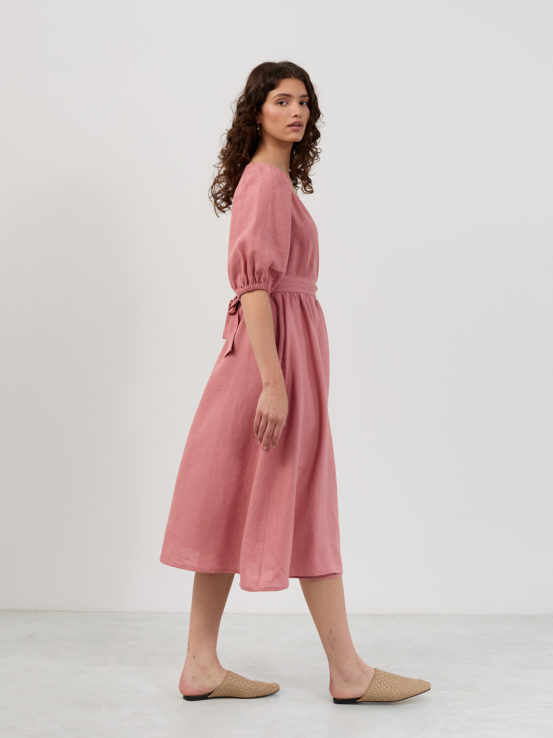 Side profile of salmon pink linen midi dress showing puff sleeves, gathered skirt and adjustable waist tie