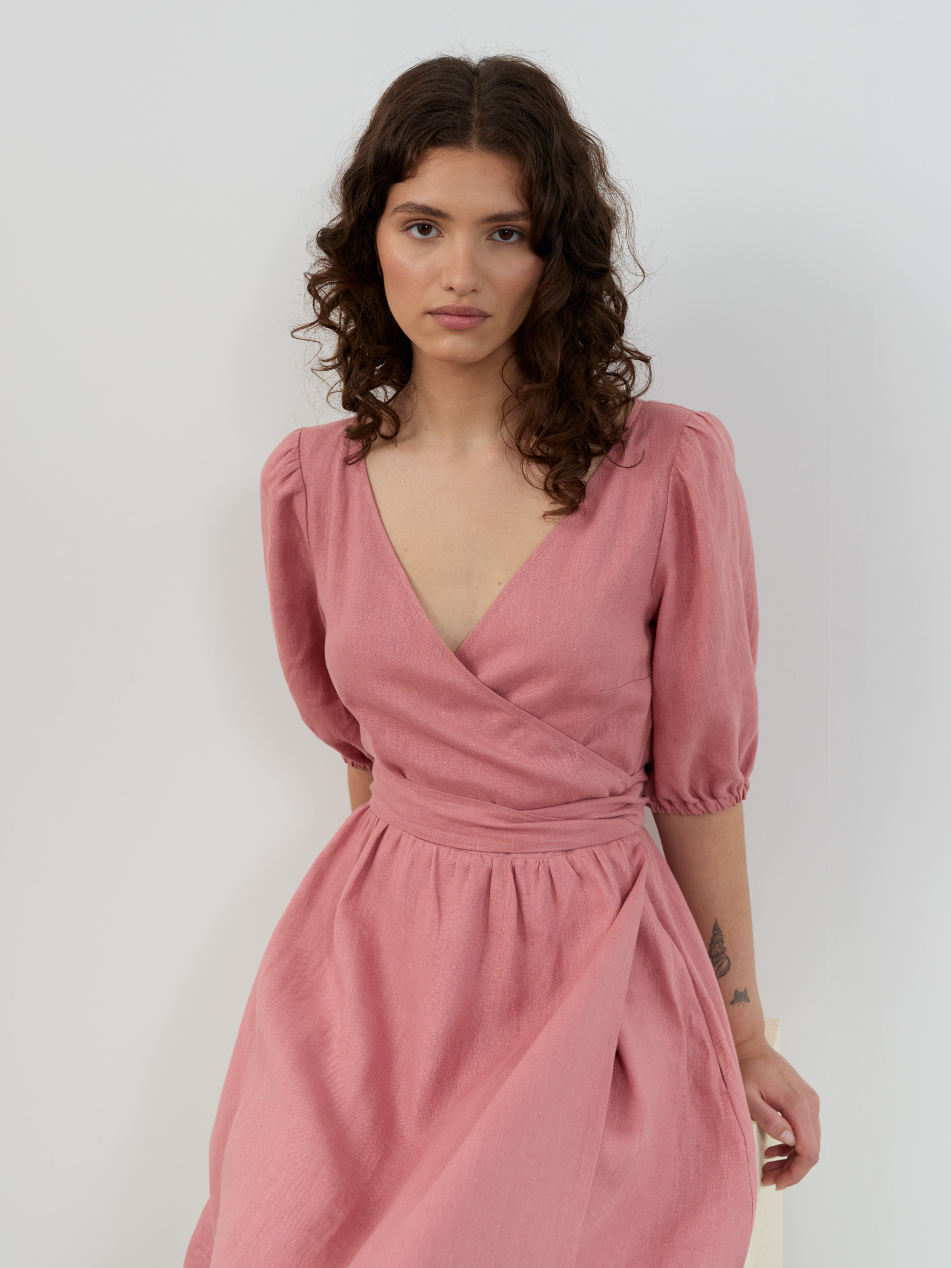 Close-up of linen midi wrap dress in salmon pink showing V neckline, waistband and gathered skirt