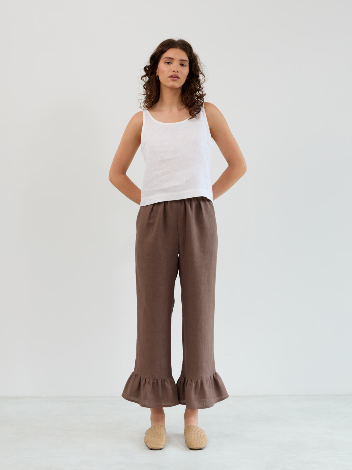 Front standing view of the Gigi cocoa linen pants showing the straight relaxed fit and ruffle bottom detail